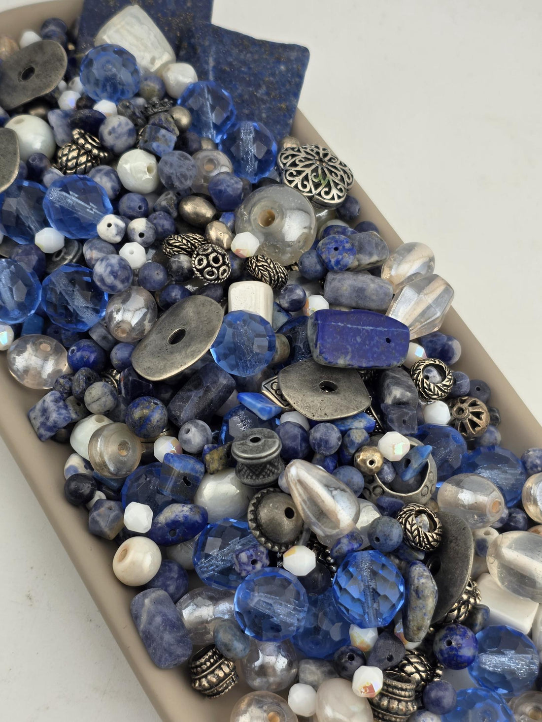 a variety of blue and silver beads, including clear and blue beads, as well as some metal beads, arranged in a visually appealing manner.