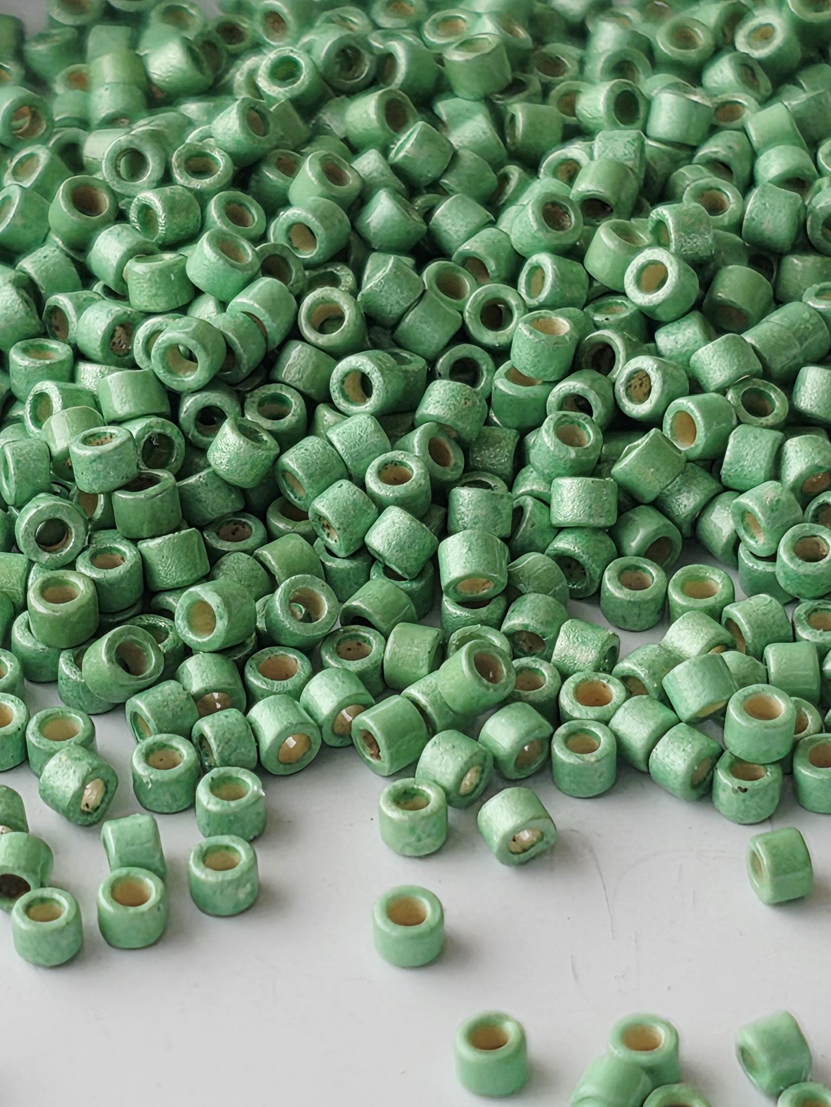 a large pile of small, green beads or objects scattered on a white surface.
