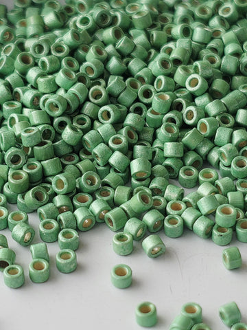 a large pile of small, green beads or objects scattered on a white surface.