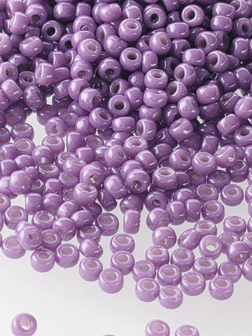 A close-up image of numerous purple beads scattered on a white background.