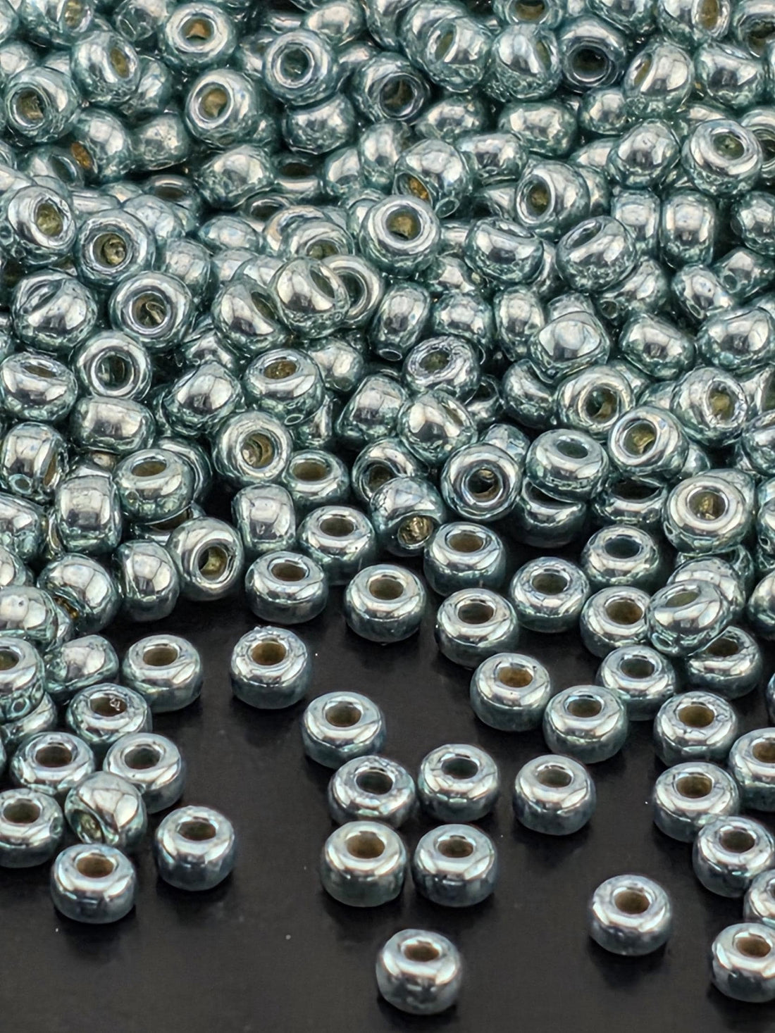 a close-up view of numerous silver-colored beads scattered across a dark background.