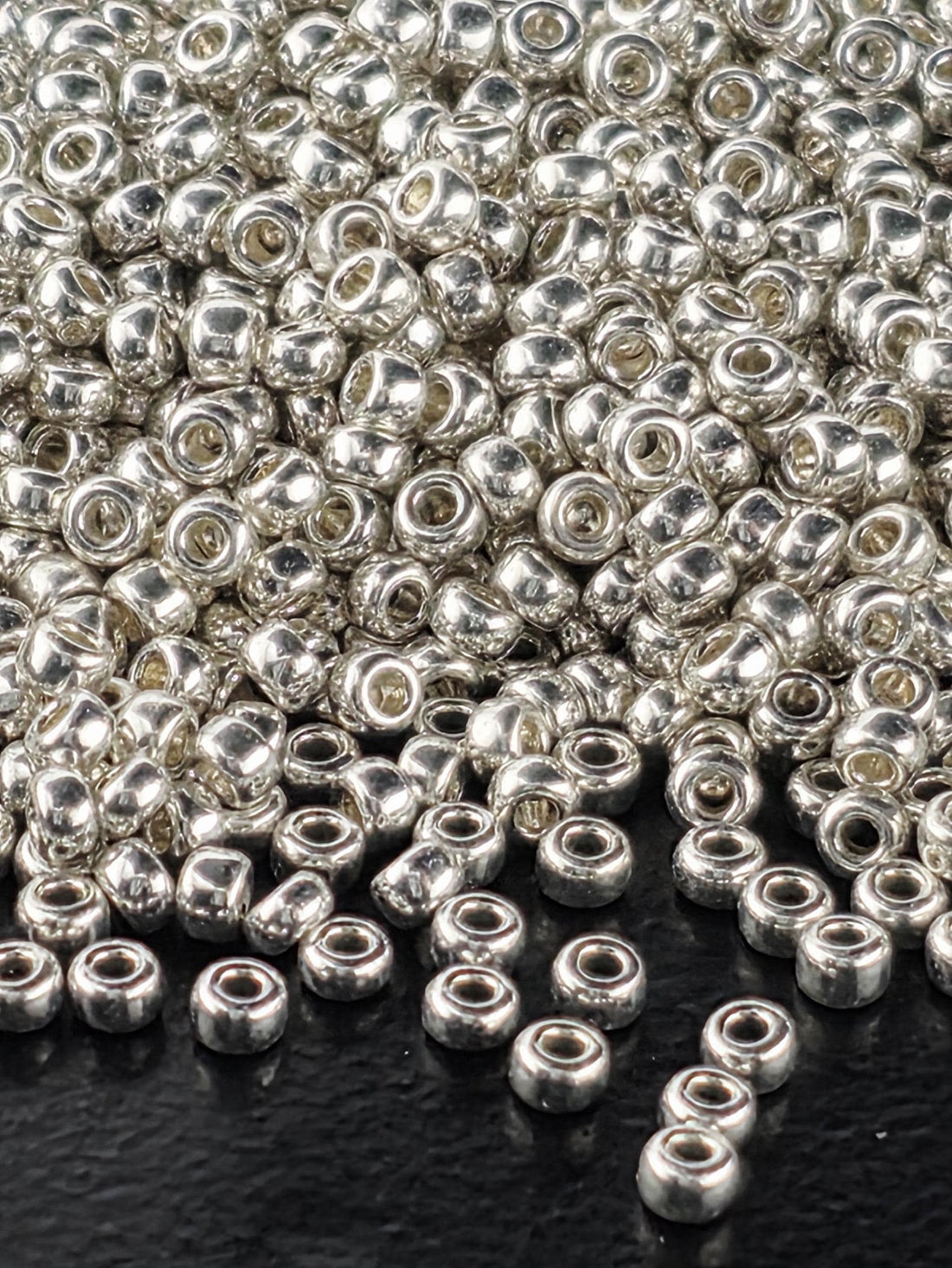 a close-up view of numerous silver-colored beads scattered on a dark surface.