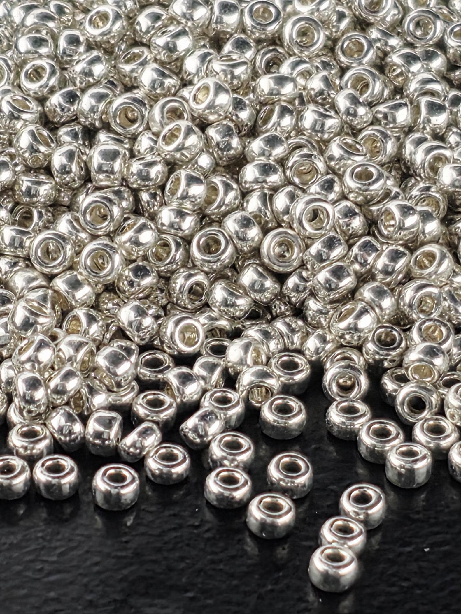 a close-up view of numerous silver-colored beads scattered on a dark surface.