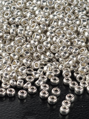 a close-up view of numerous silver-colored beads scattered on a dark surface.