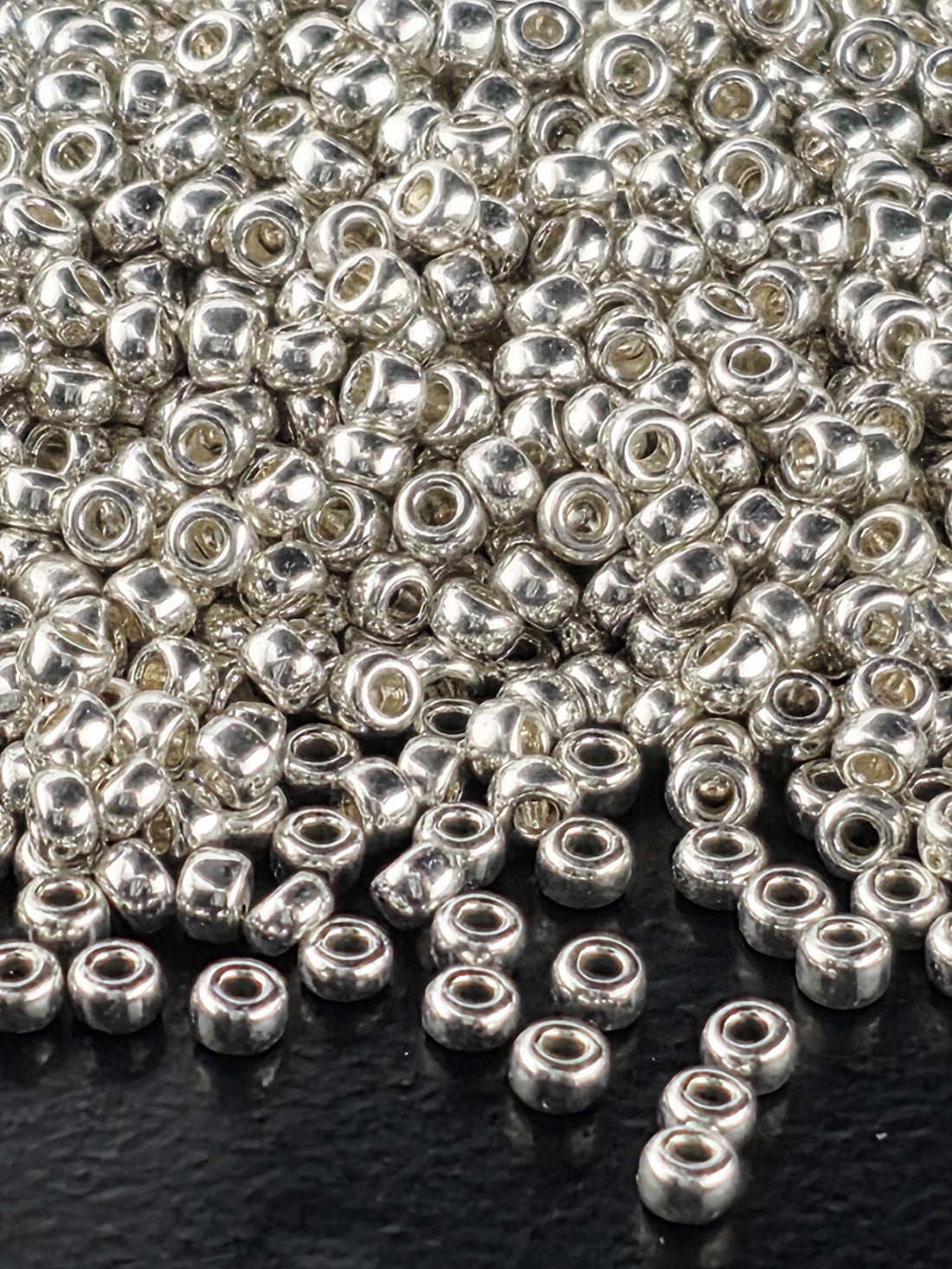 a close-up view of numerous silver-colored beads scattered on a dark surface.