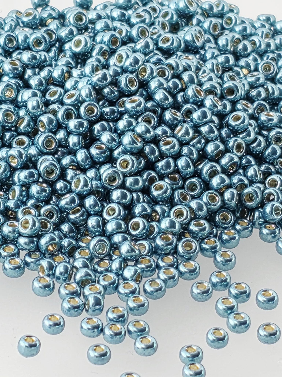 a large pile of small, shiny blue beads scattered across a white background.