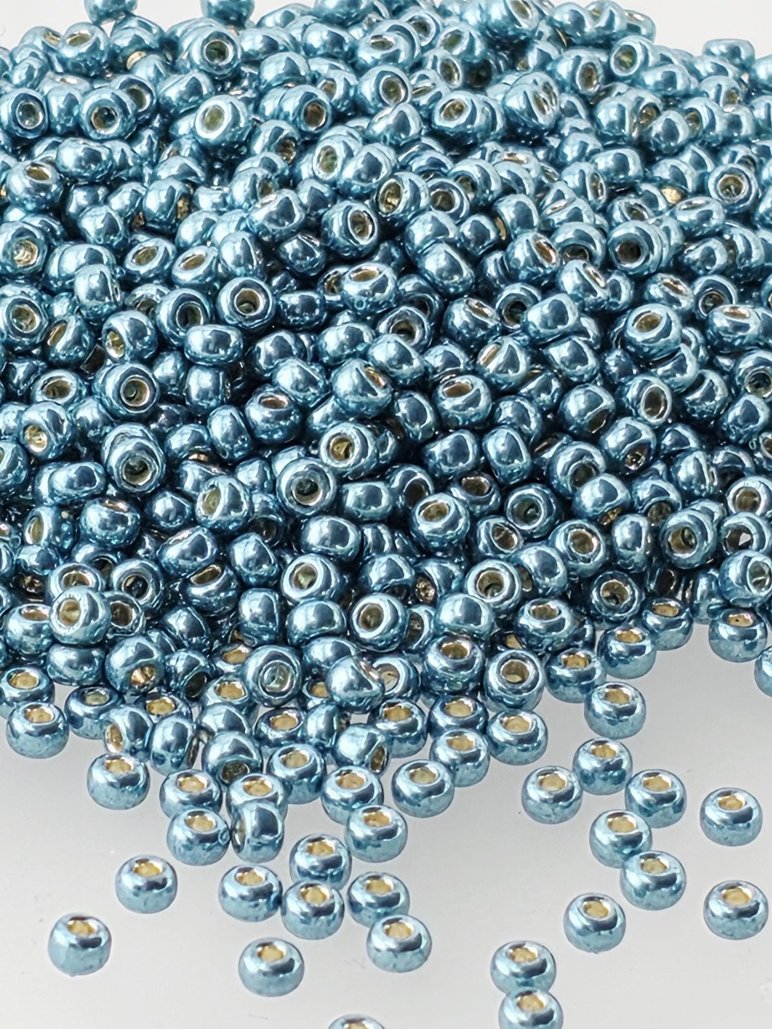 a large pile of small, shiny blue beads scattered across a white background.