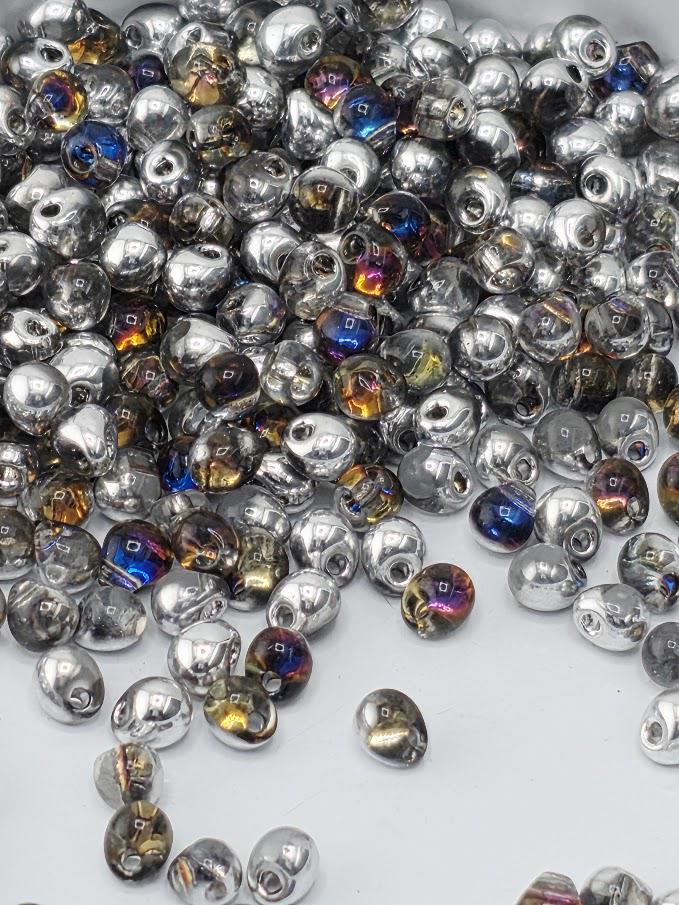 a large pile of multicolored glass beads scattered on a white surface.