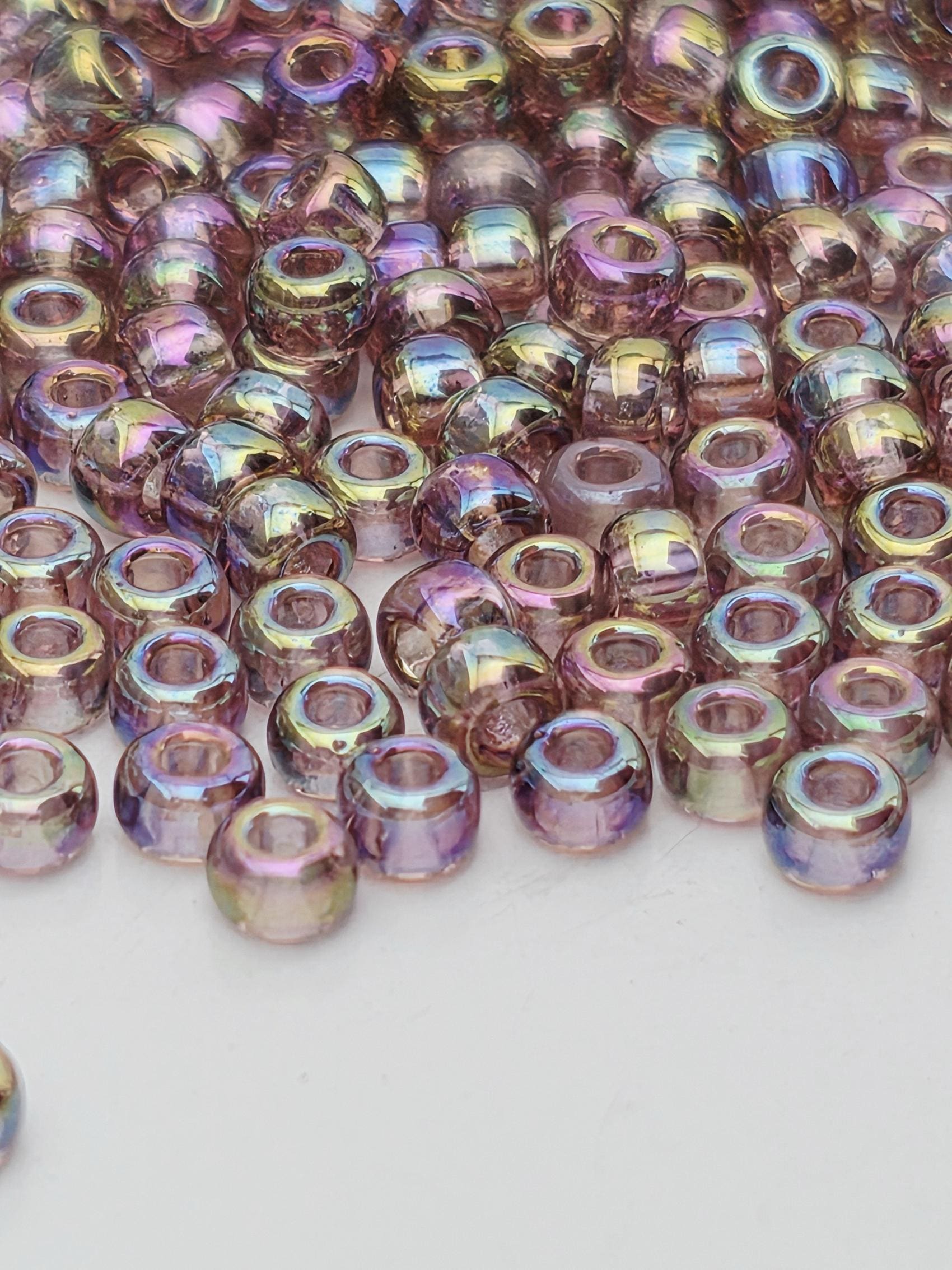 A close-up image of numerous multicolored beads, likely made of glass or plastic, scattered on a white surface.