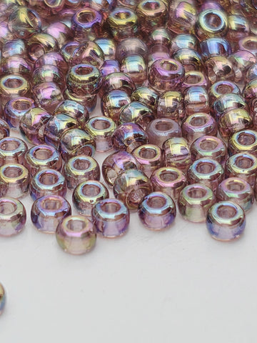 A close-up image of numerous multicolored beads, likely made of glass or plastic, scattered on a white surface.