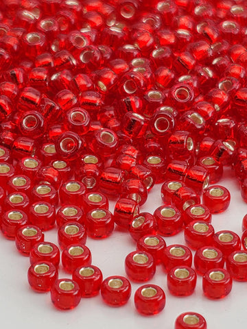 The image is a close-up of numerous red glass beads scattered across a surface.