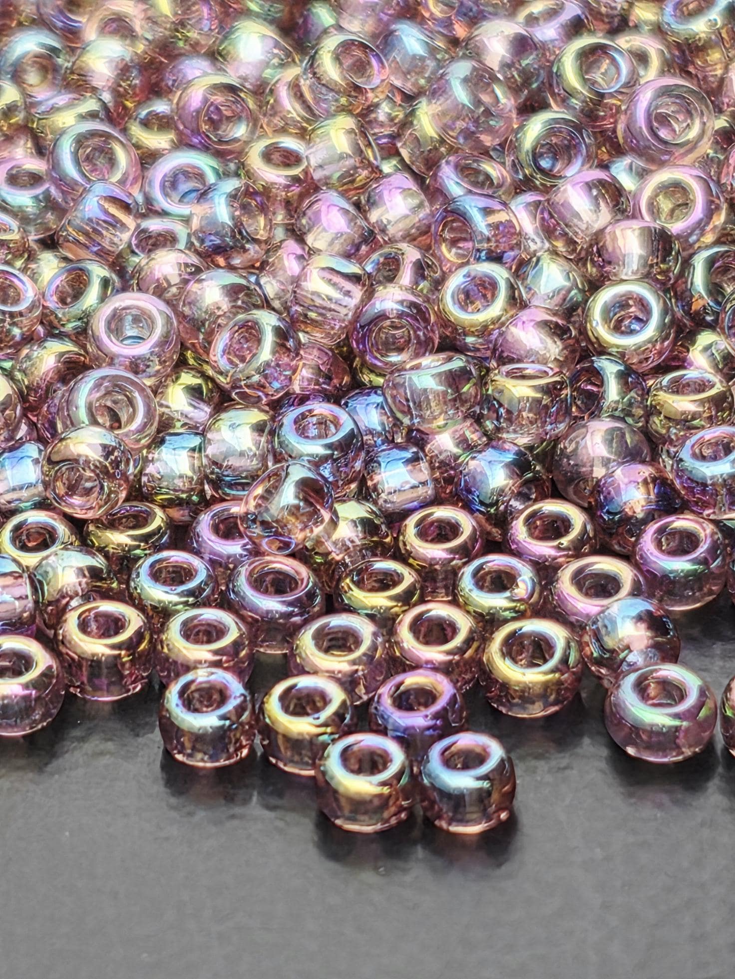 A close-up image of numerous multicolored beads, possibly made of glass or plastic, scattered and overlapping each other.