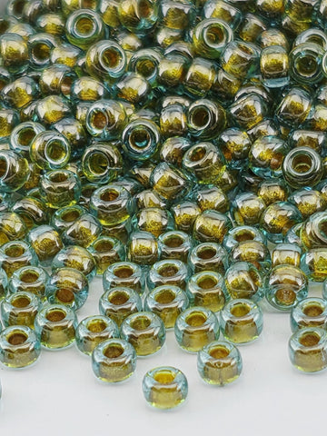 a close-up view of numerous small, clear glass beads in various shades of green and yellow, scattered across a surface.