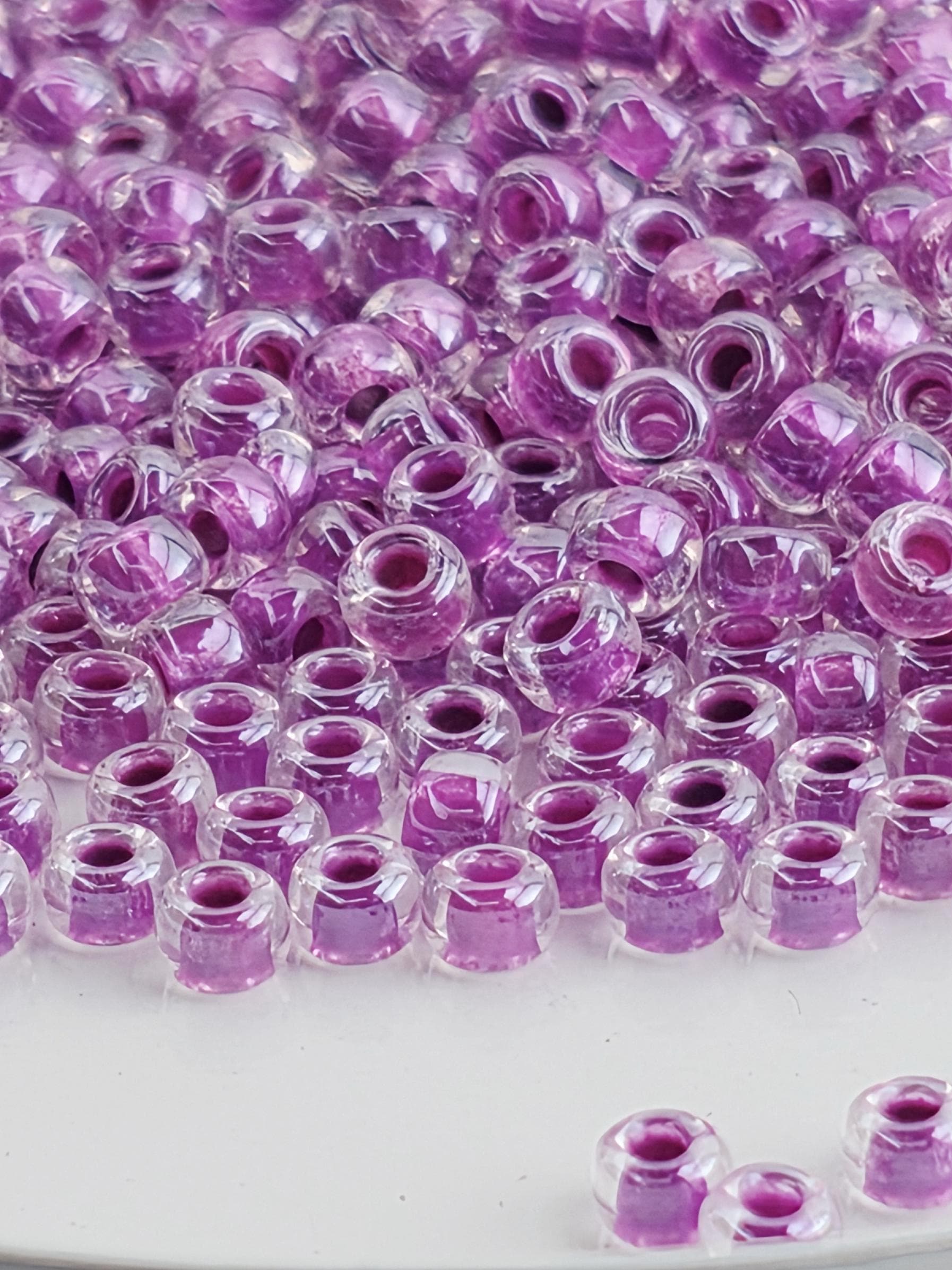 The image is a close-up of numerous clear and purple glass beads arranged in a pattern.