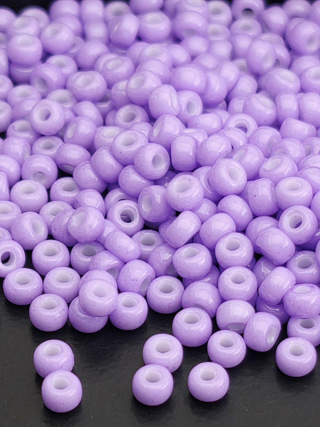 A close-up image of numerous purple beads scattered on a white surface.