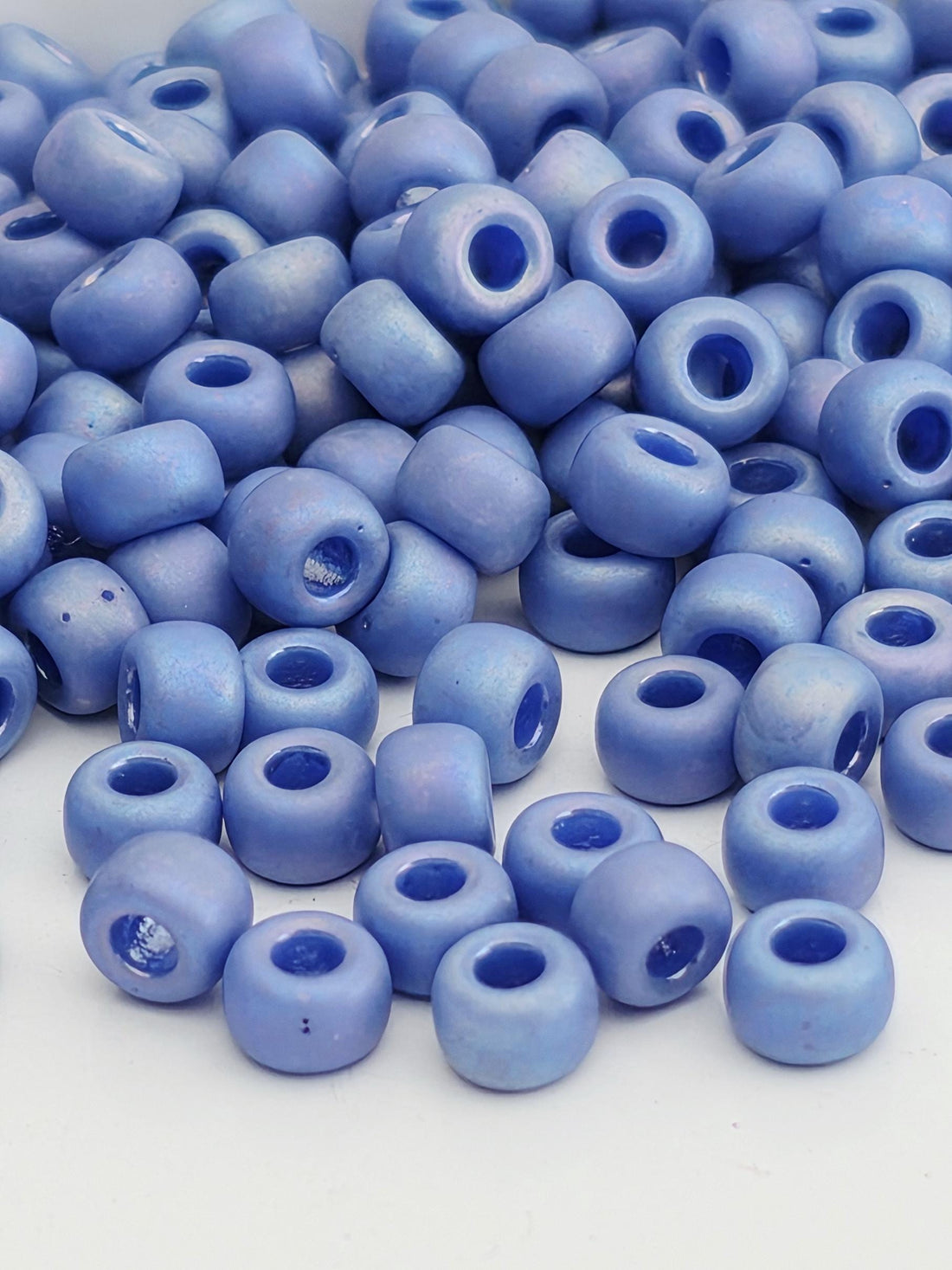A pile of blue beads with holes scattered on a white background.