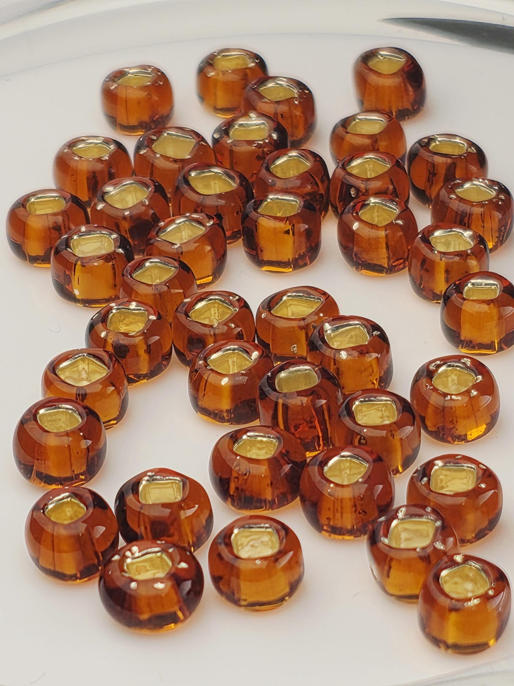 a collection of small, round, amber-colored glass beads arranged on a white surface.