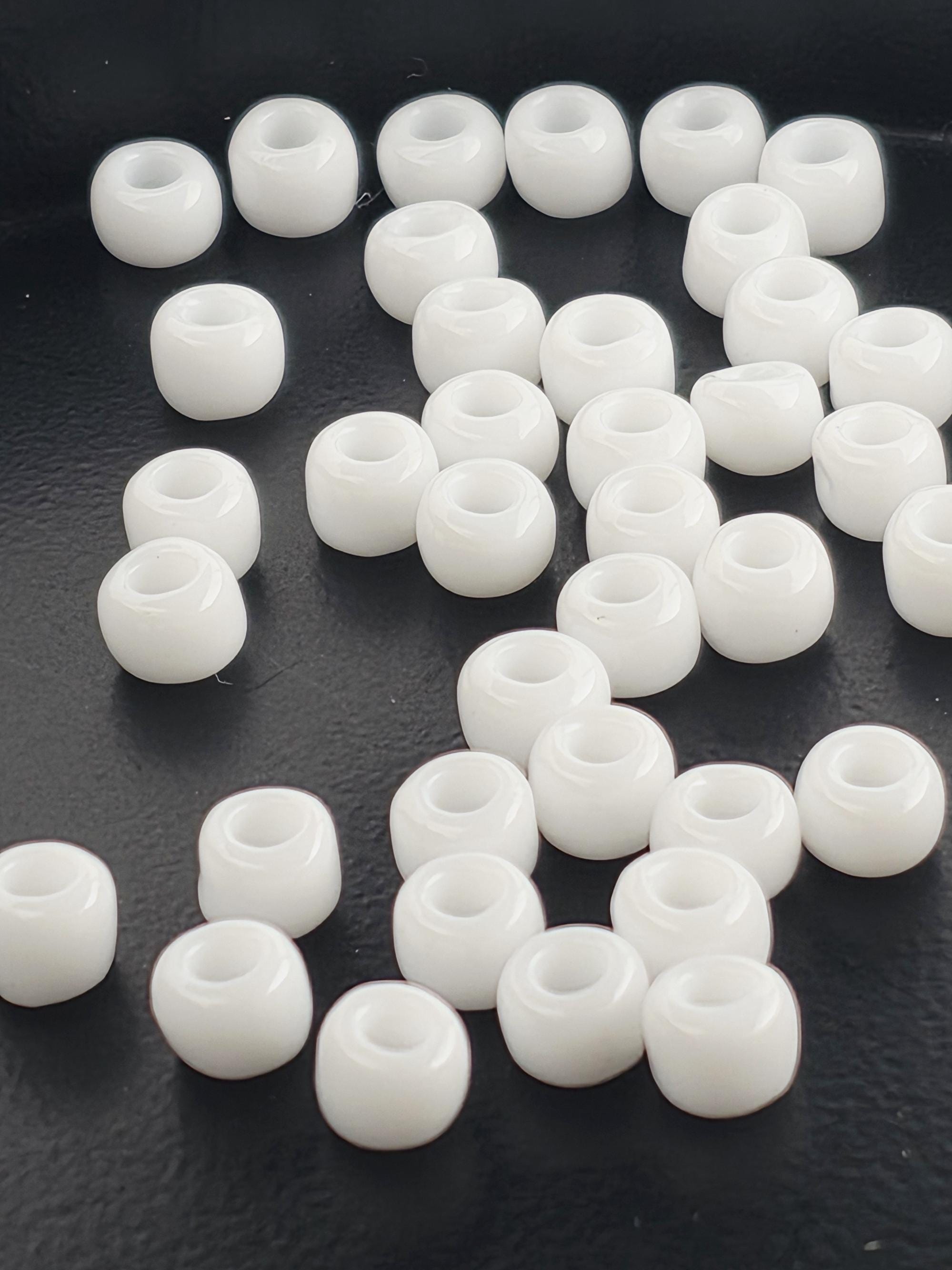 a collection of white beads scattered on a dark surface.