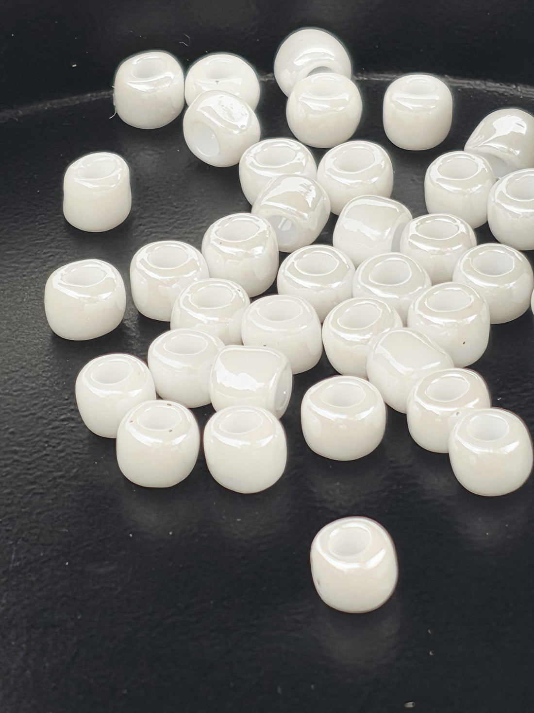 a collection of white glass beads scattered on a black surface.