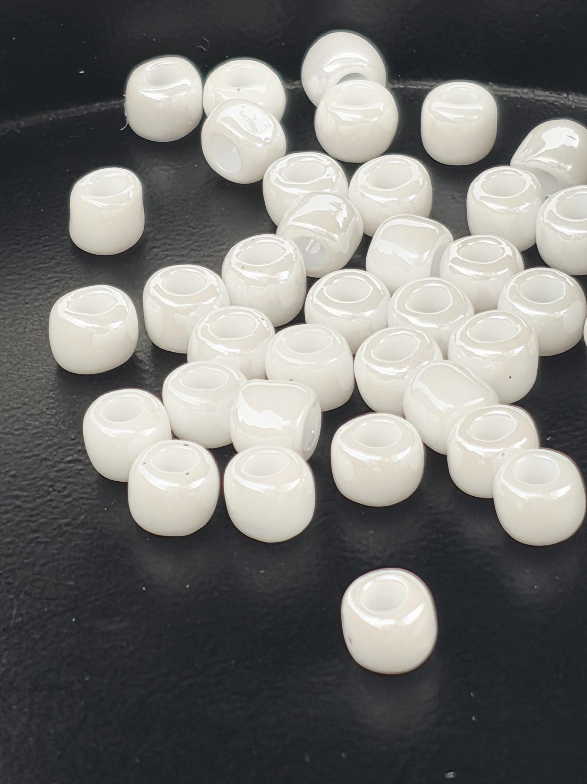 a collection of white glass beads scattered on a black surface.