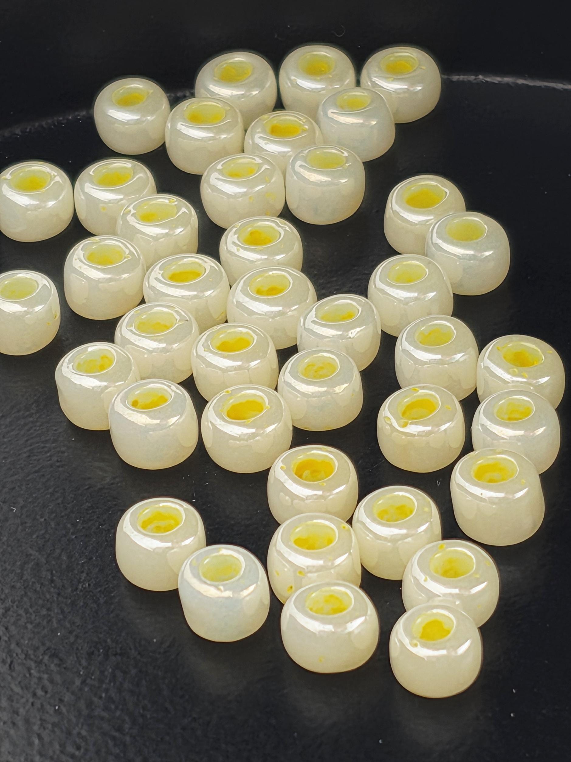 a collection of small, white beads with yellow centers, arranged on a dark surface.