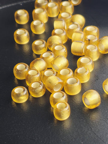 a collection of small, round, yellow beads scattered on a dark surface.