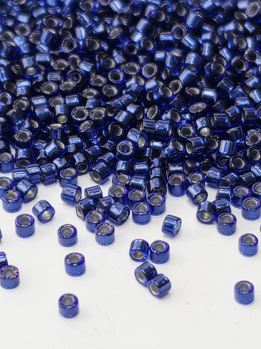 a close-up view of numerous blue and silver beads scattered across a white surface.