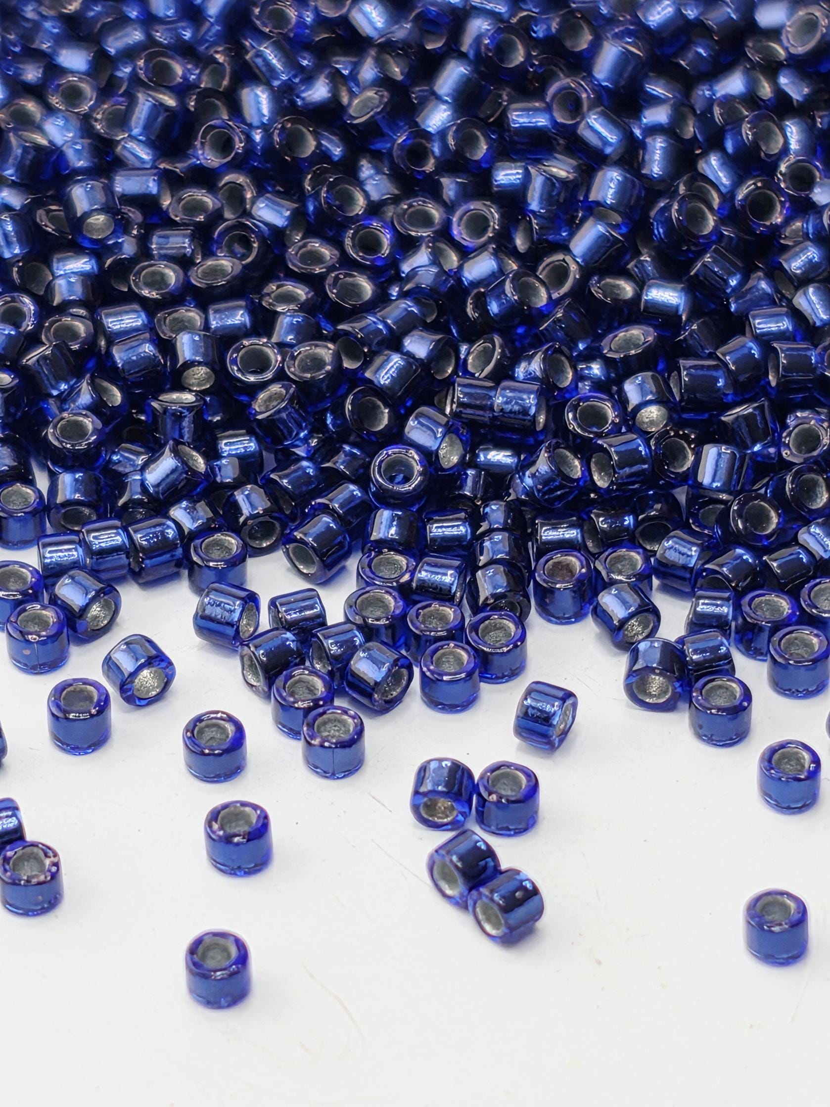 a close-up view of numerous blue and silver beads scattered across a white surface.