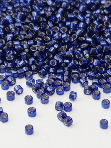 a close-up view of numerous blue and silver beads scattered across a white surface.
