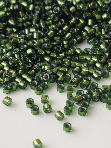 a large pile of green and silver beads scattered on a white surface.
