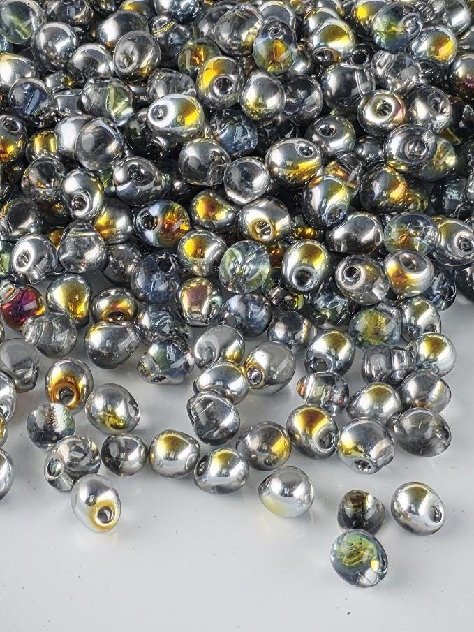 a large pile of multicolored glass beads scattered on a white surface.