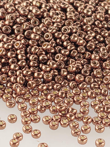 The image is a close-up of numerous copper-colored beads or beads scattered across a surface.