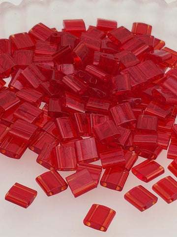 a large pile of red, clear plastic beads or blocks scattered on a white surface.