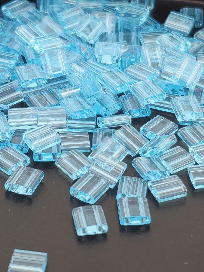 numerous small, clear plastic beads scattered across a dark surface.
