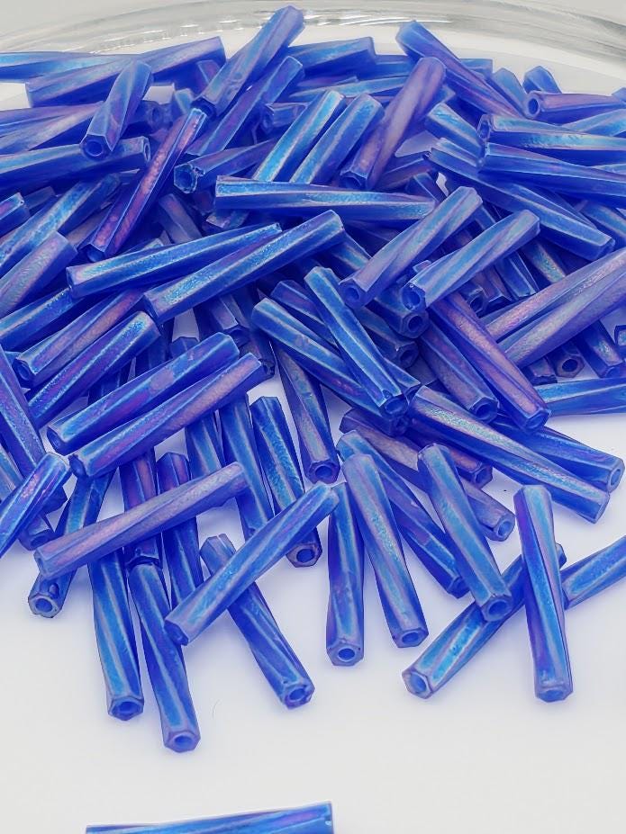 a pile of blue and purple hexagonal beads on a white surface.