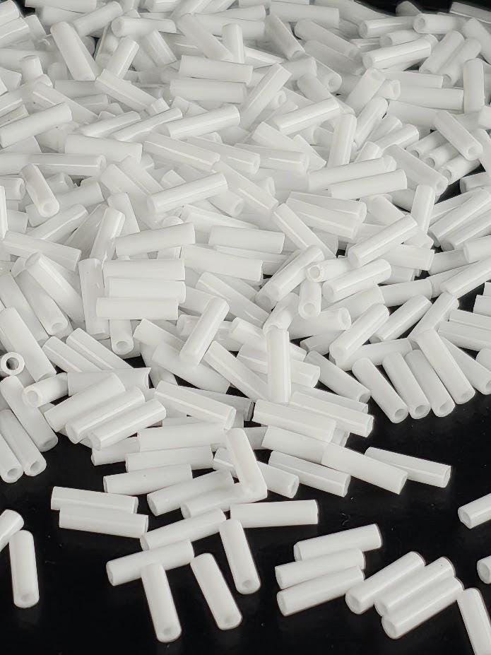 numerous white cylindrical objects scattered across a dark background.