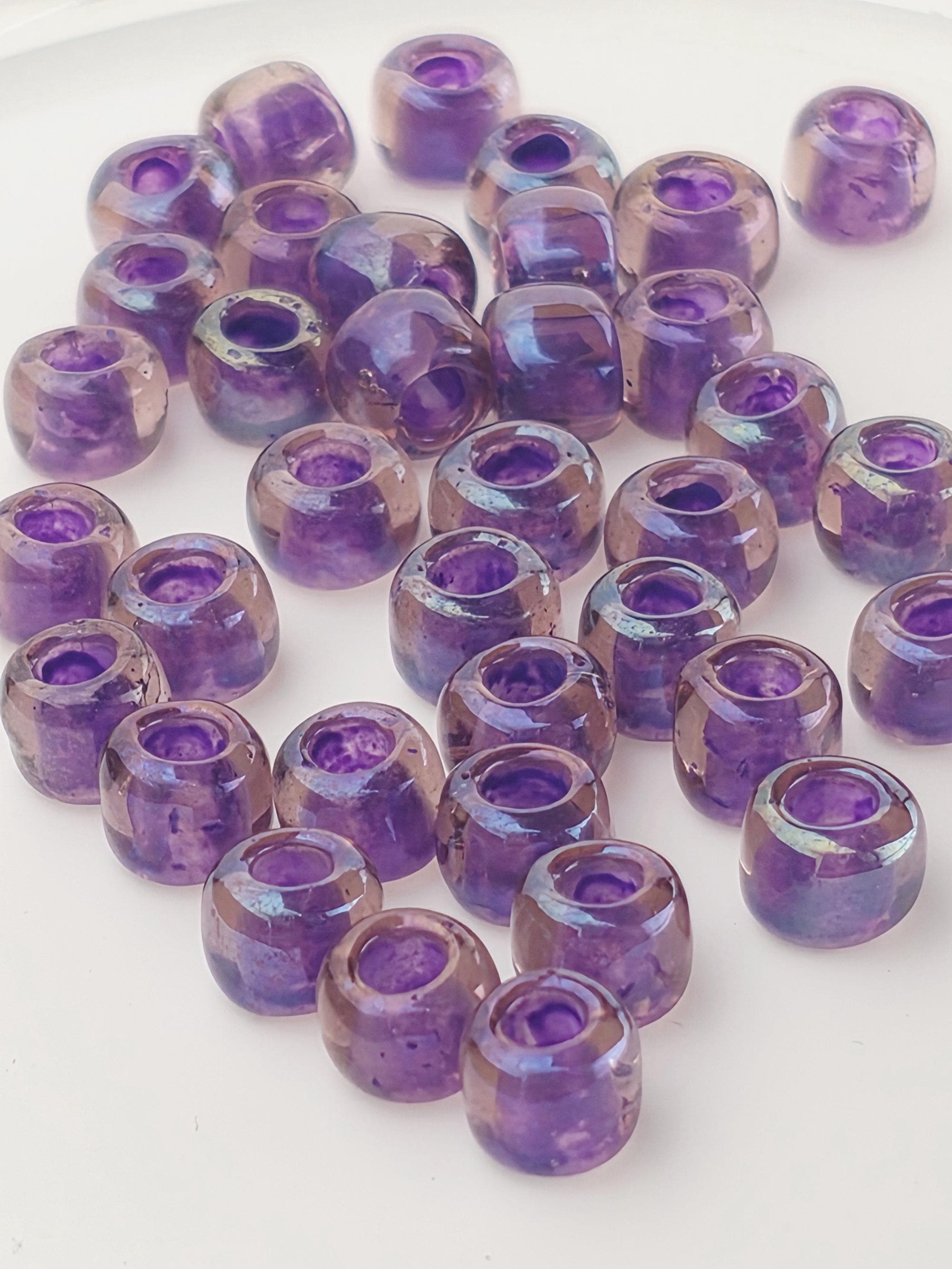 a collection of purple glass beads arranged on a white surface.