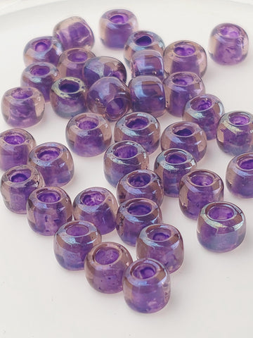 a collection of purple glass beads arranged on a white surface.