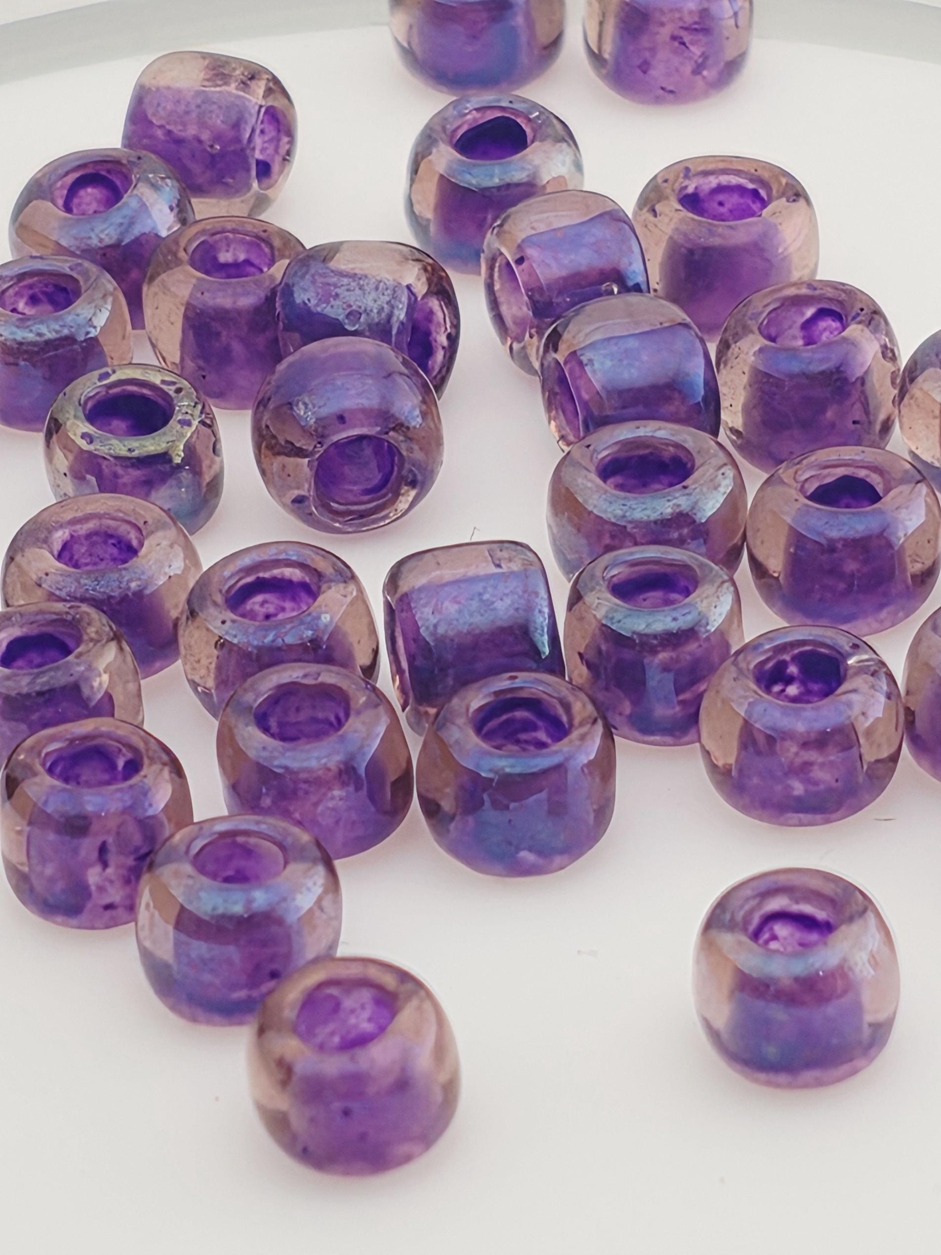 a collection of purple glass beads scattered on a white surface.