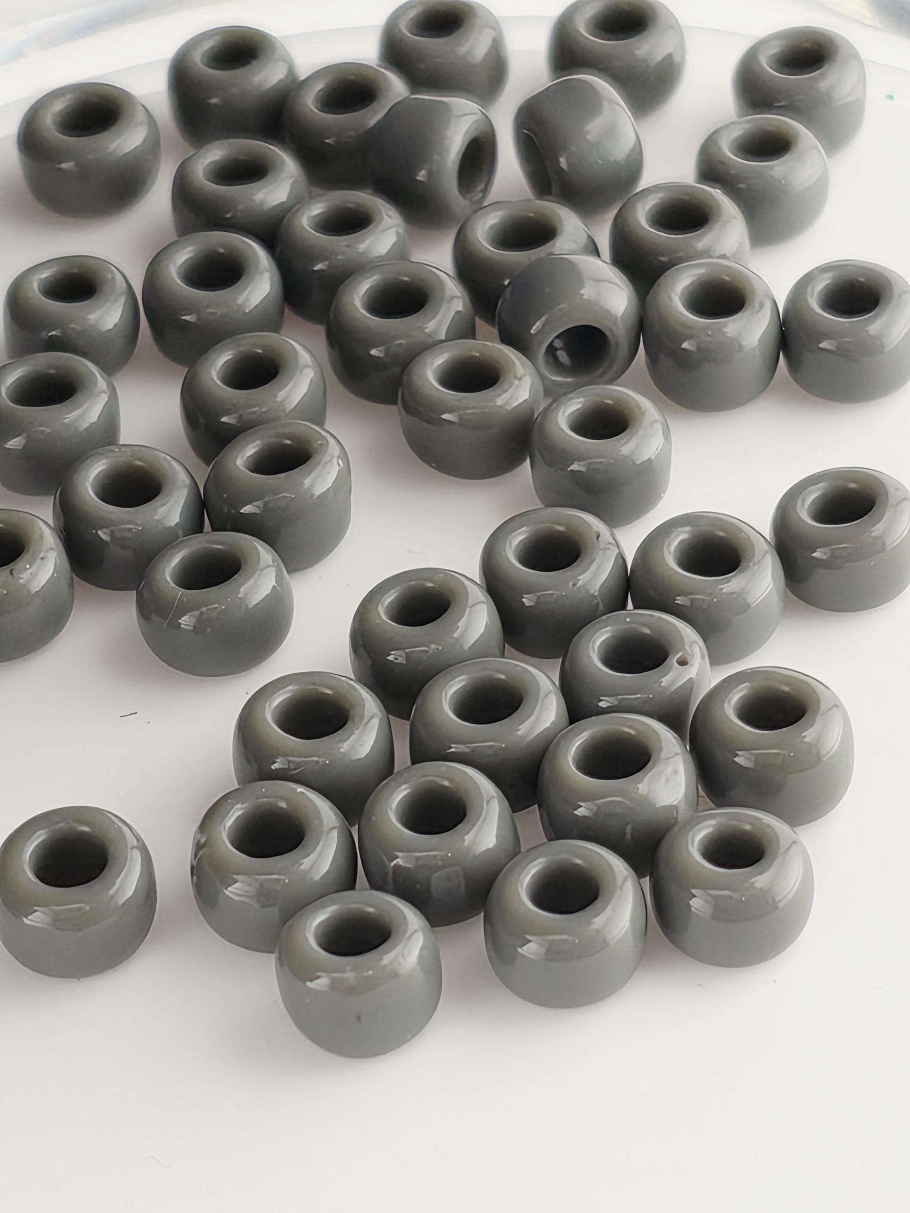 a collection of grey beads or objects arranged in a pattern, possibly on a white surface.