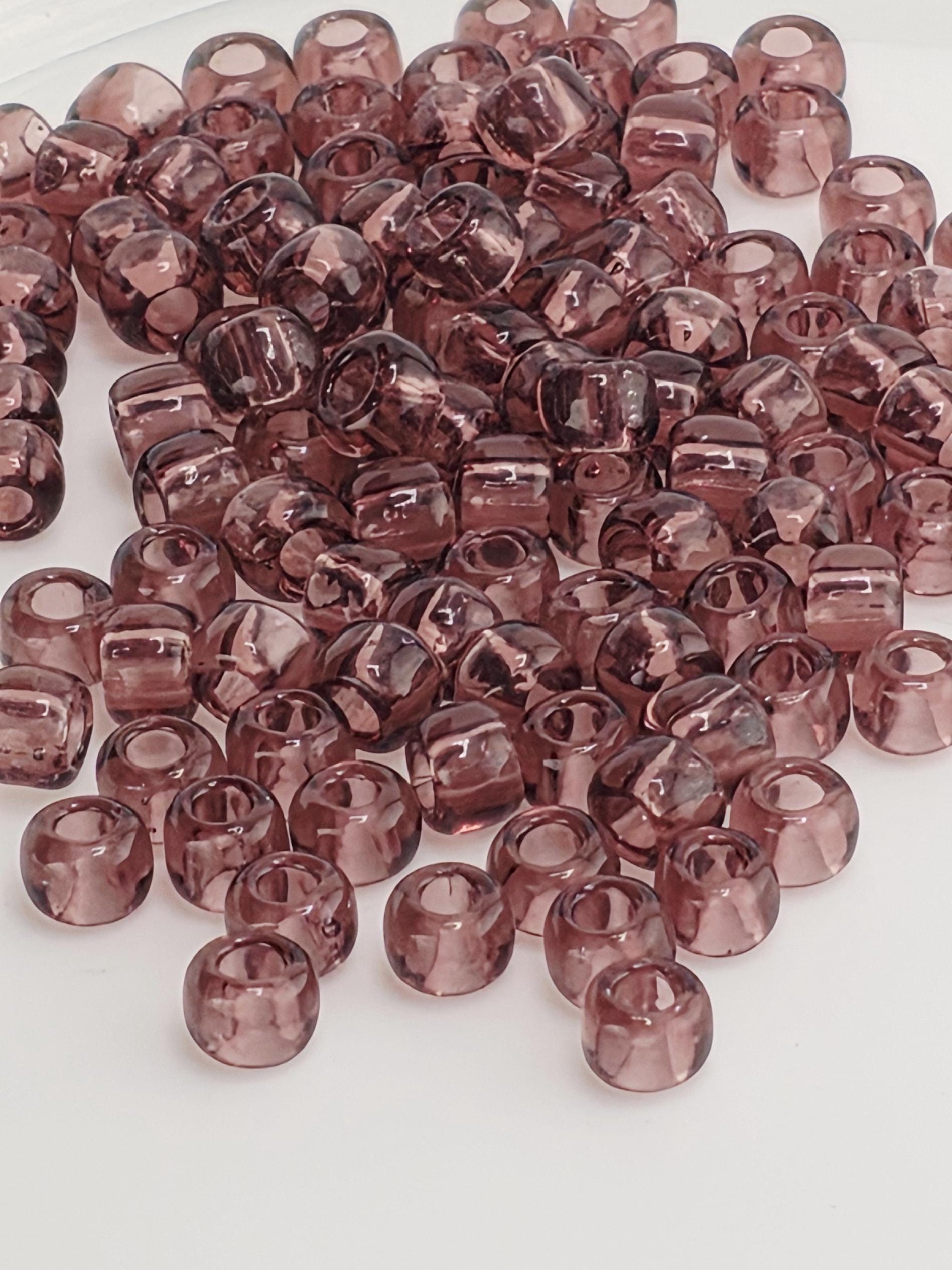 A pile of small, clear beads in various shades of pink or purple.