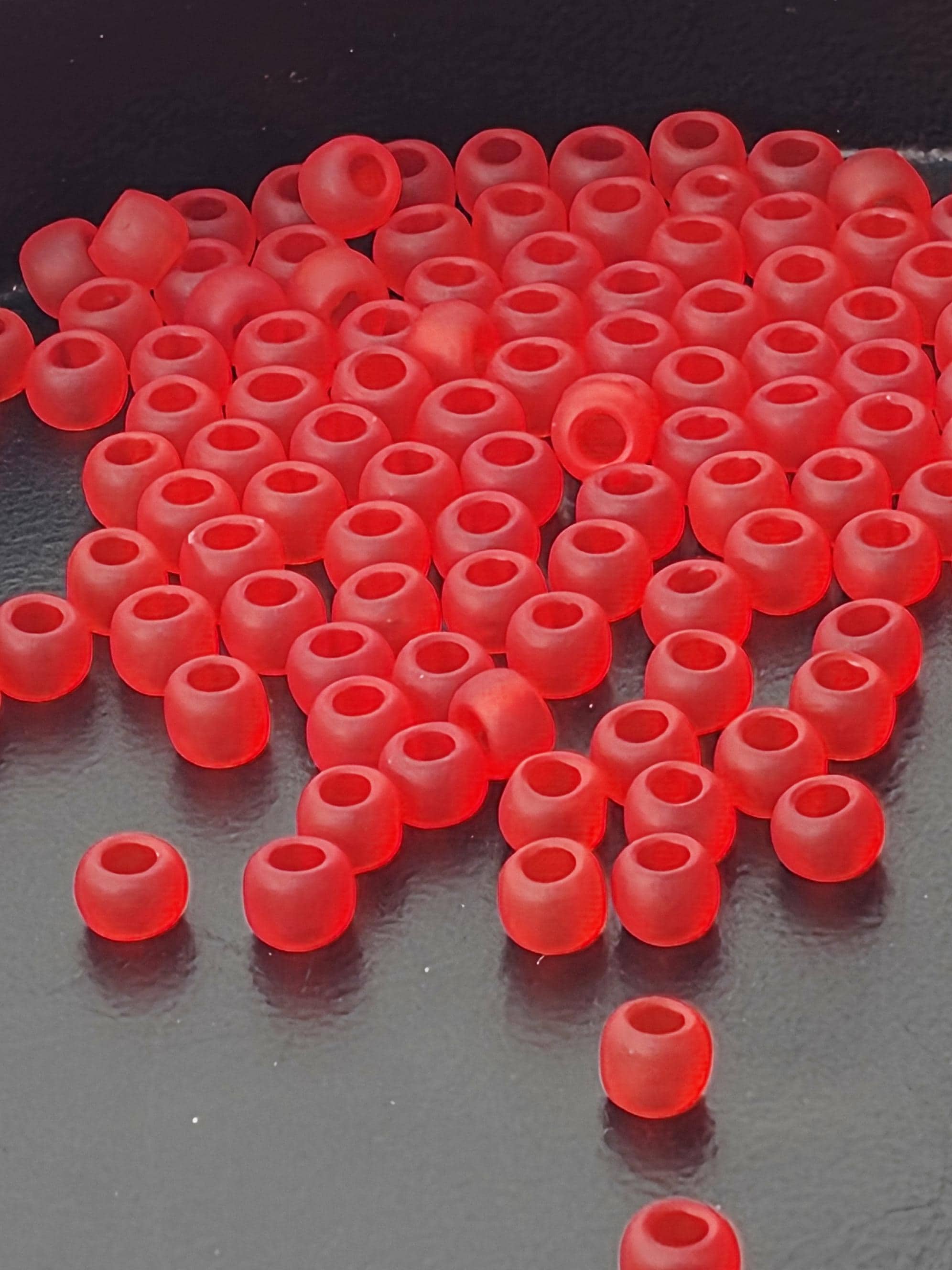 a large number of red plastic beads or earplugs scattered on a dark surface.