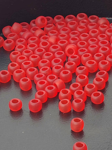 a large number of red plastic beads or earplugs scattered on a dark surface.