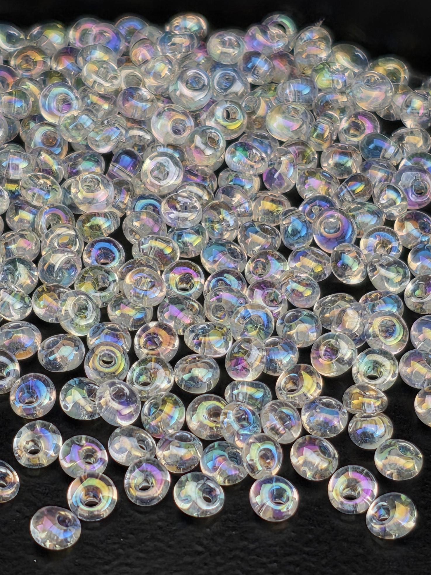 a close-up view of numerous clear, iridescent beads scattered across a dark background.