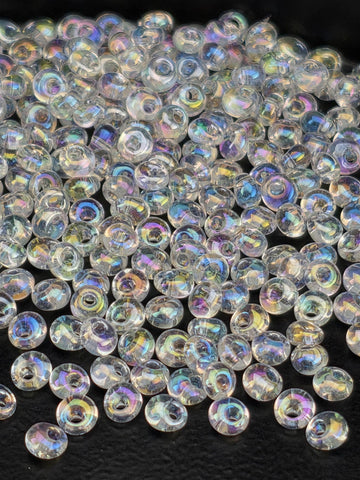 a close-up view of numerous clear, iridescent beads scattered across a dark background.