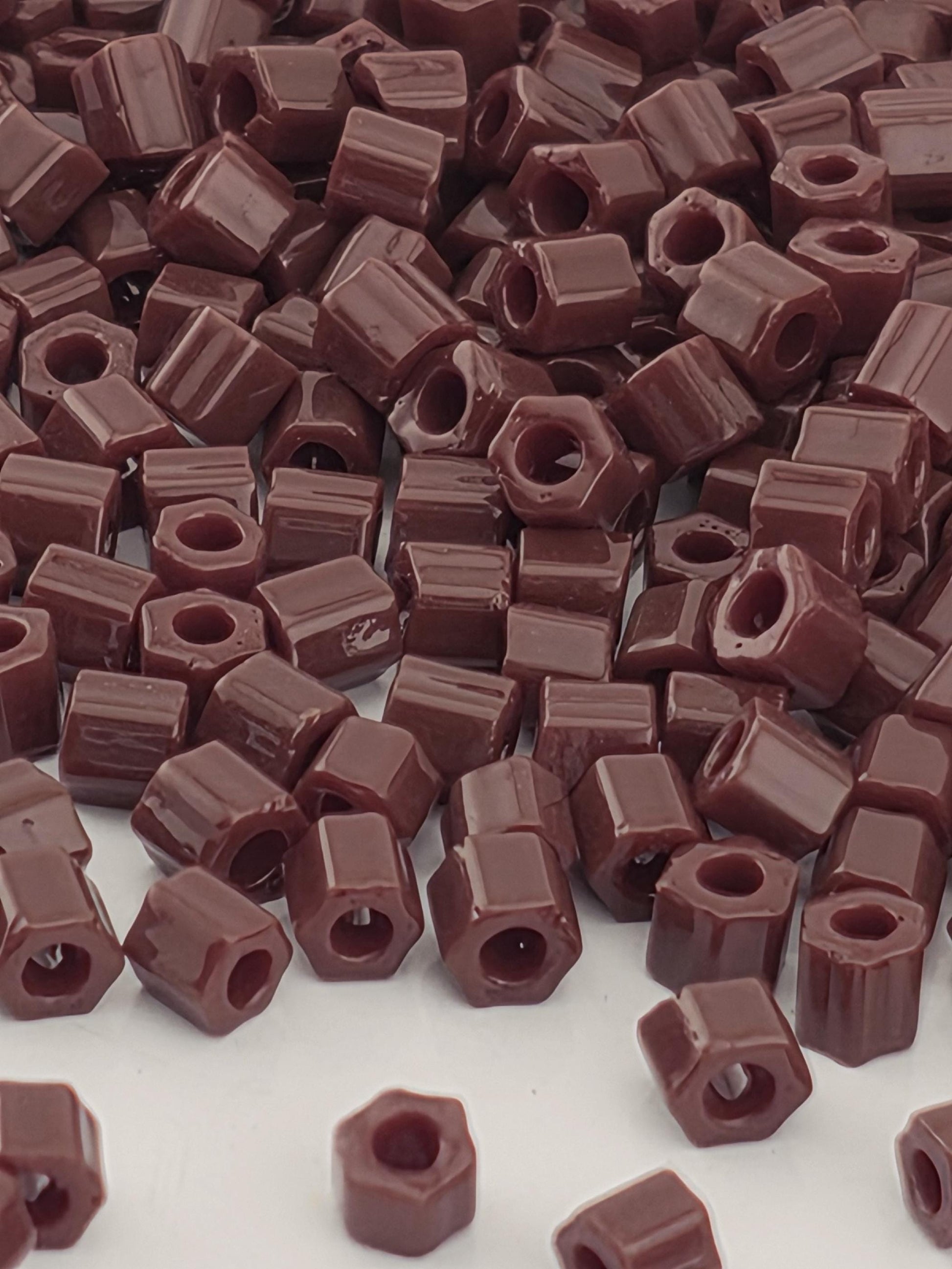 a close-up view of a pile of brown, square-shaped objects, which appear to be small, rectangular-shaped items. The objects are scattered and overlapping, creating a visually interesting and textured composition.