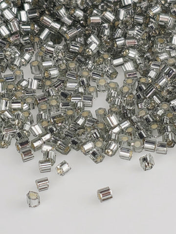 The image is a close-up of numerous silver and white beads or crystals, scattered and overlapping each other.