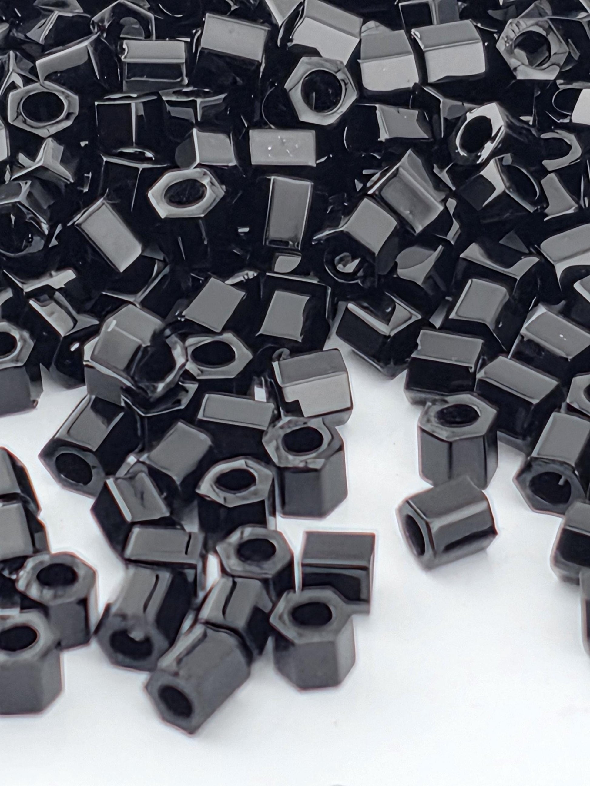 numerous black hexagonal nuts and bolts scattered across a white background.