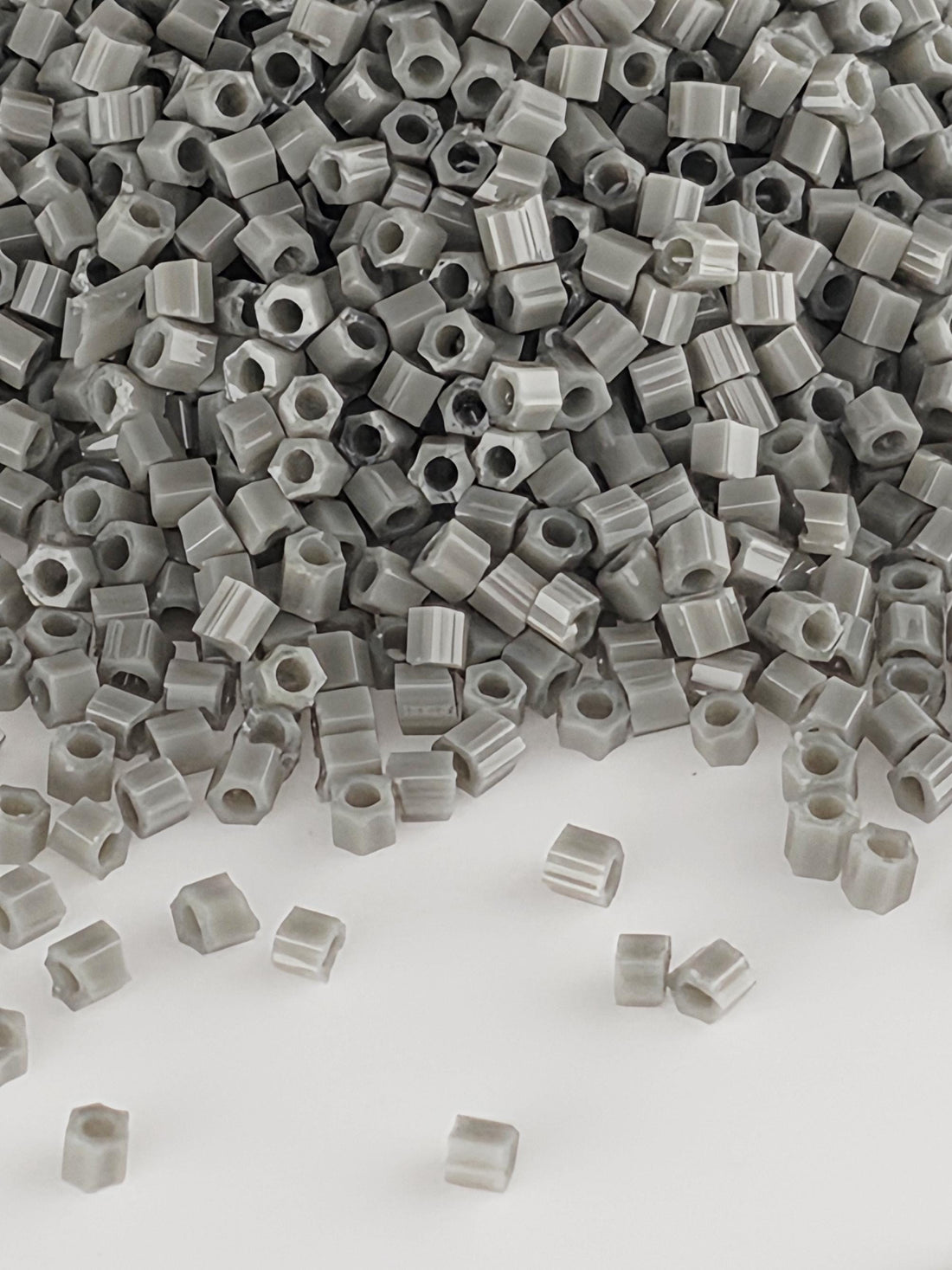 a large pile of small, gray plastic beads or nuts scattered on a white background.