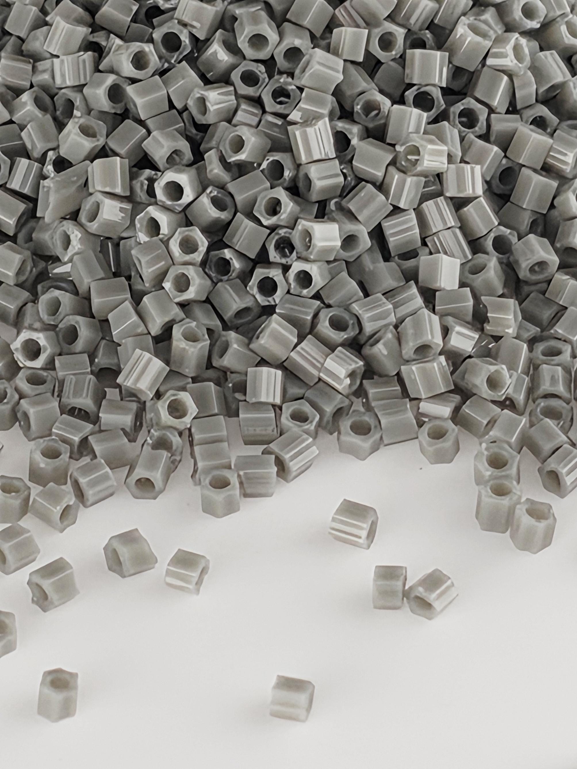 a large pile of small, gray plastic beads or nuts scattered on a white background.